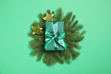 Gift box and fir tree branches on green background, flat lay