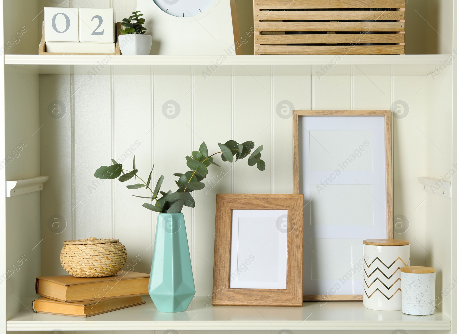 Photo of White shelving unit with photo frames and different decorative elements