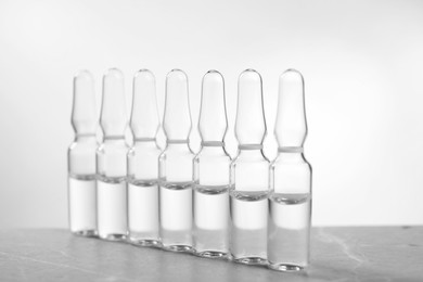 Photo of Pharmaceutical ampoules with medication on grey table against light background