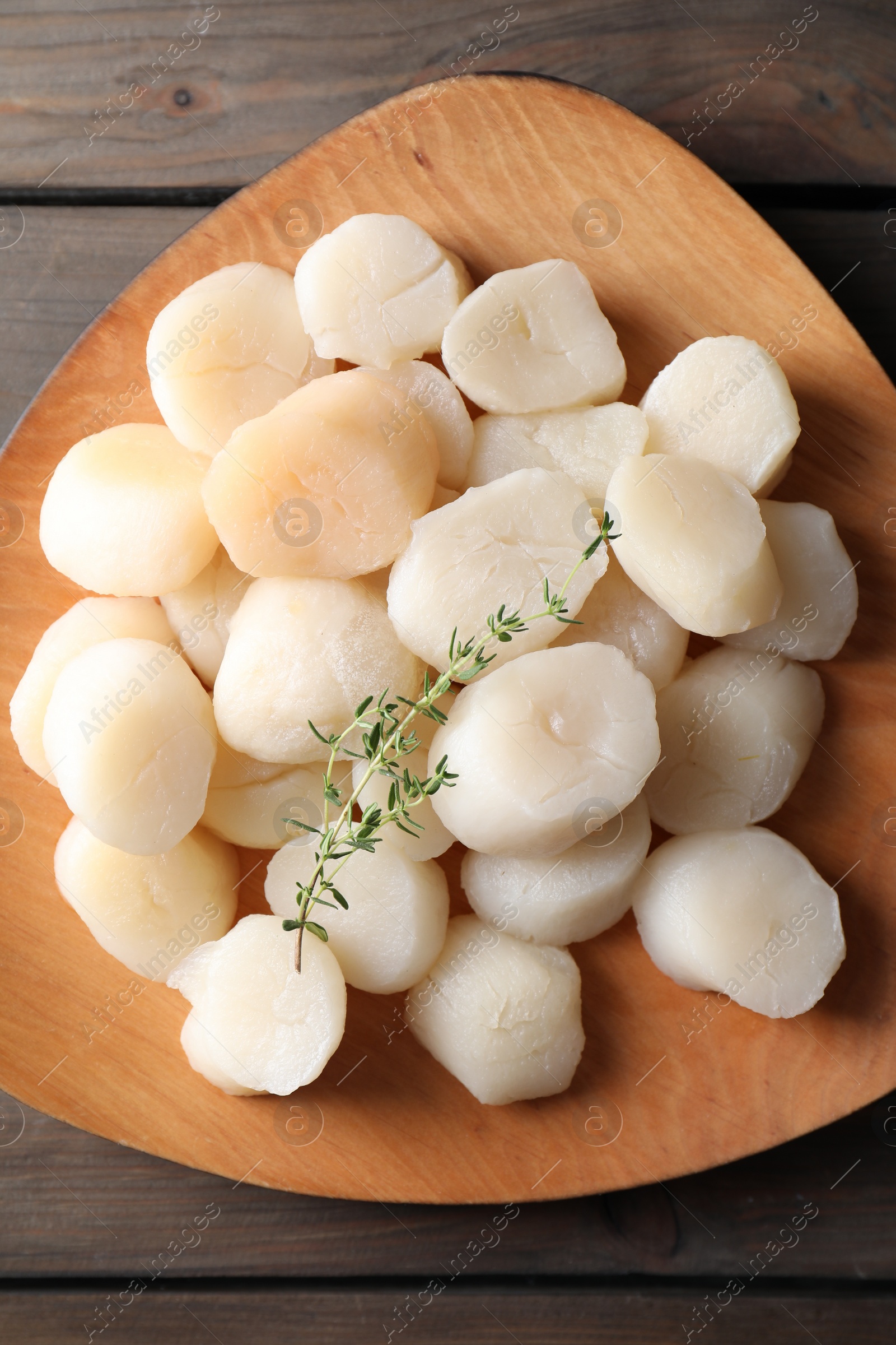 Photo of Fresh raw scallops and thyme on wooden table, top view