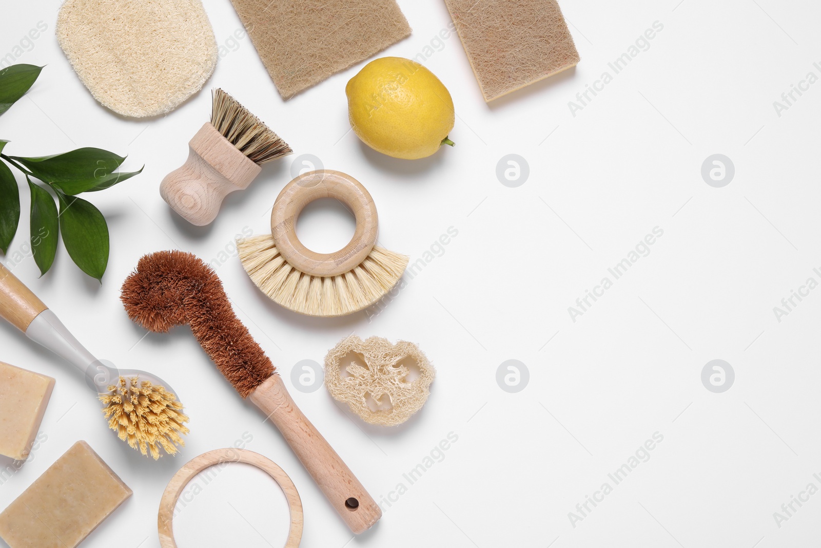 Photo of Cleaning brushes, lemon, baking soda, sponges and leaves on white background, flat lay. Space for text