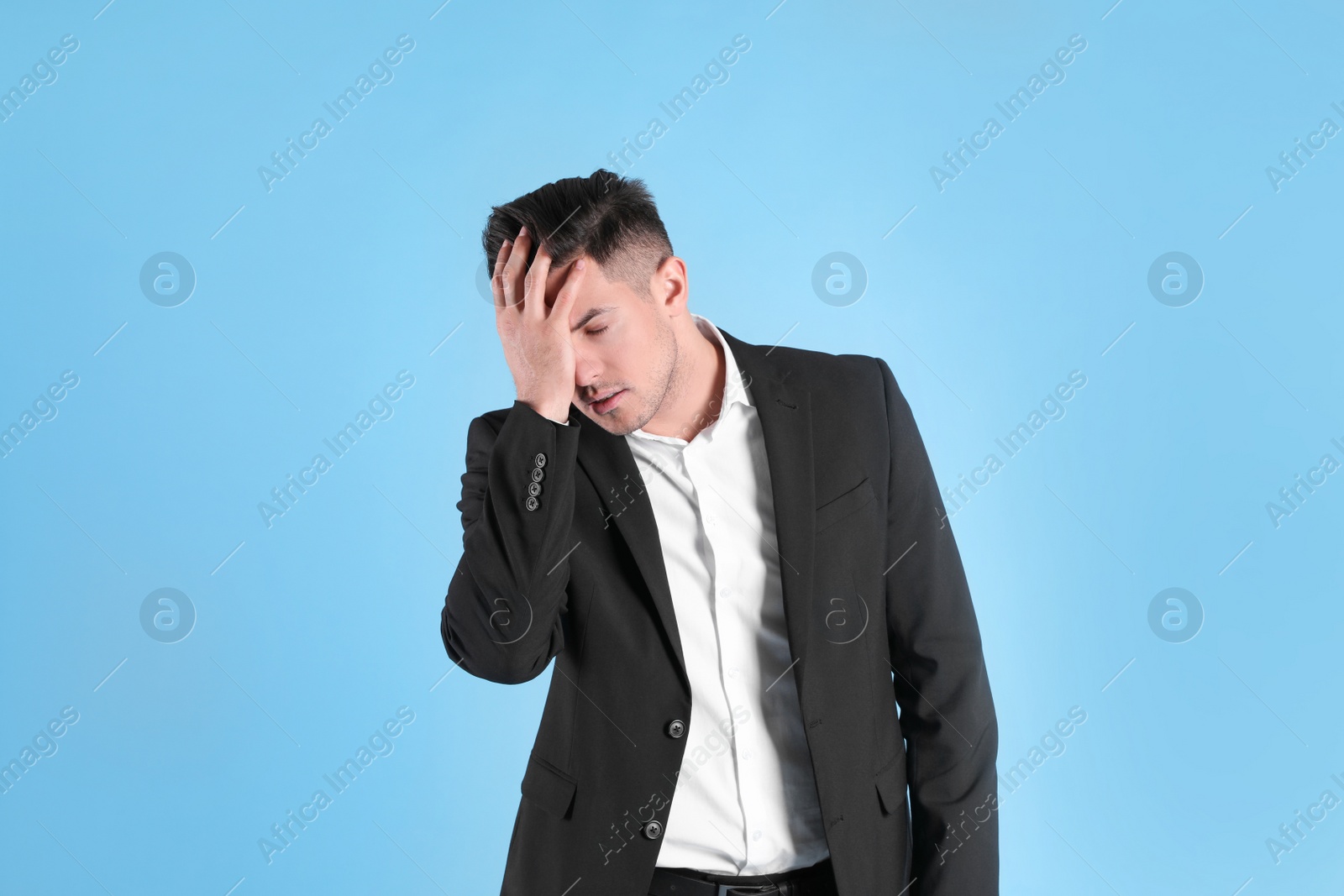 Photo of Upset man in suit on light blue background
