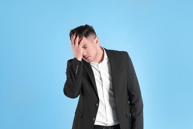 Photo of Upset man in suit on light blue background