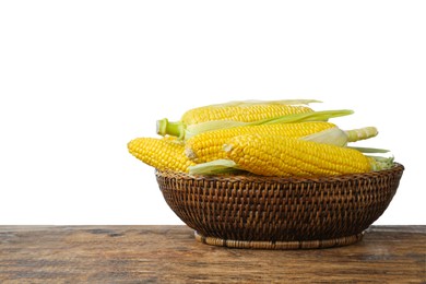 Tasty fresh corn cobs in wicker bowl on wooden table against white background