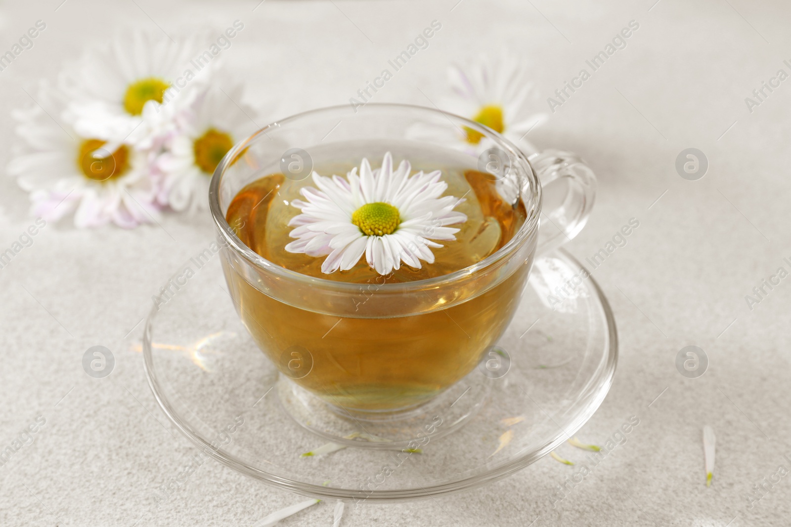 Photo of Glass cup of delicious chamomile tea on white table