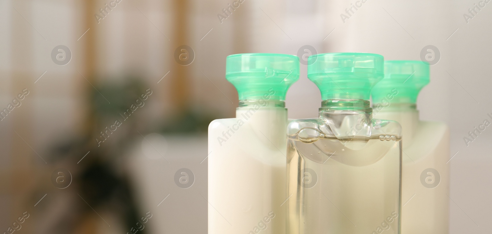 Photo of Mini bottles of cosmetic products on blurred background, closeup. Space for text