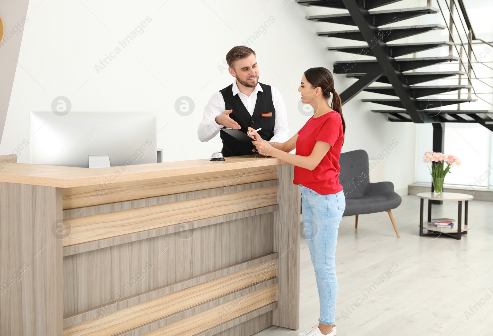 Photo of Professional receptionist working with client at desk in modern hotel