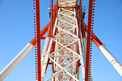 Photo of Beautiful large Ferris wheel against blue sky, bottom view
