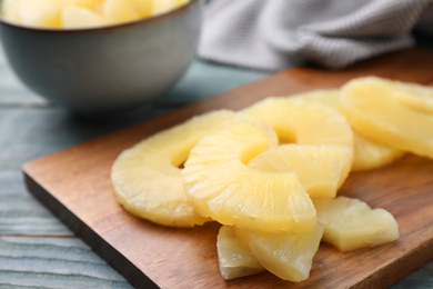 Photo of Tasty canned pineapple on wooden board, closeup