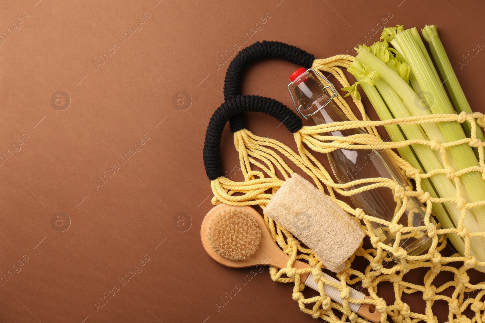 Photo of Fishnet bag with different items on brown background, top view and space for text. Conscious consumption