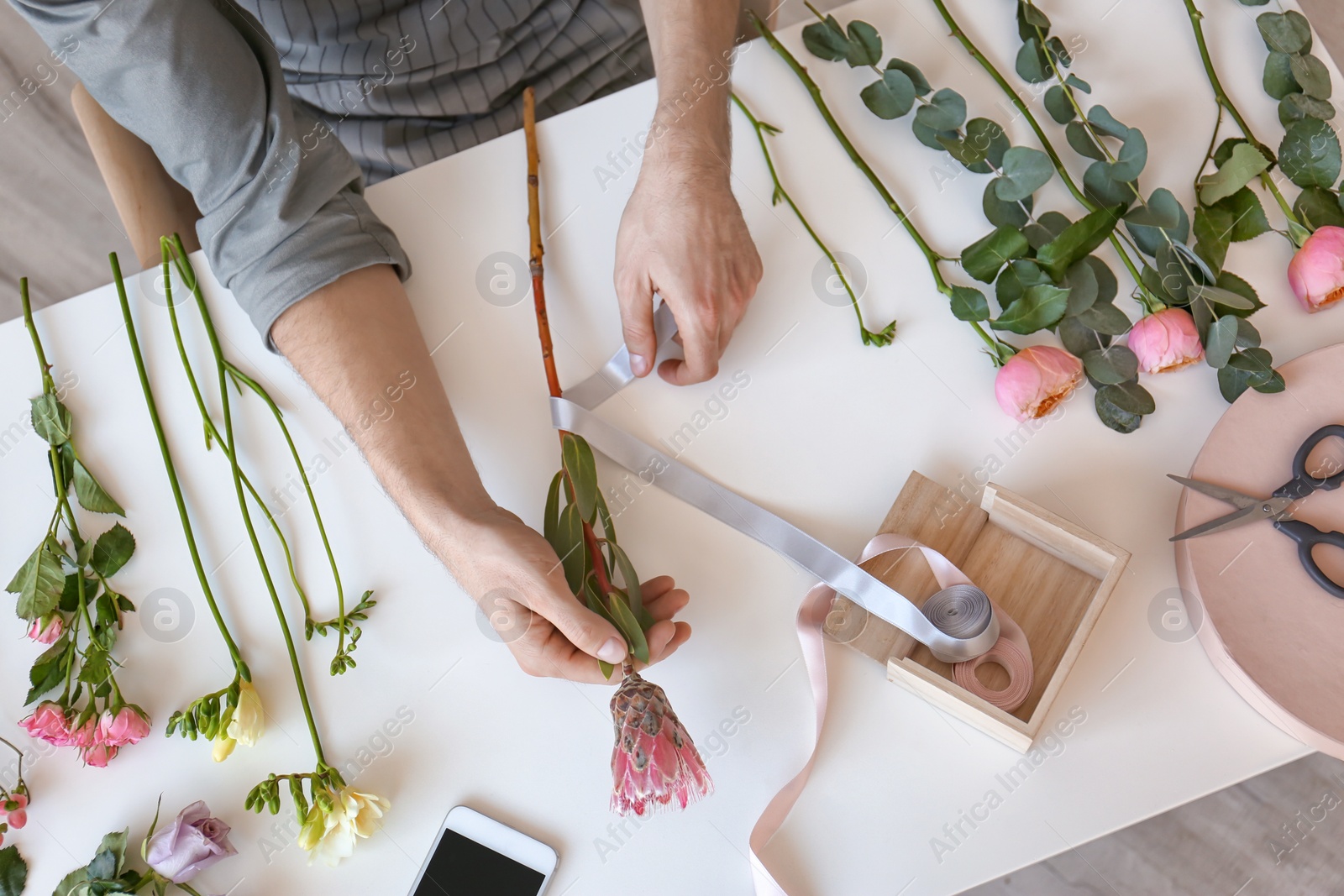 Photo of Male florist creating beautiful bouquet at table, top view