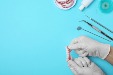 Photo of Dentist holding tooth prosthesis on color background, top view. Space for text