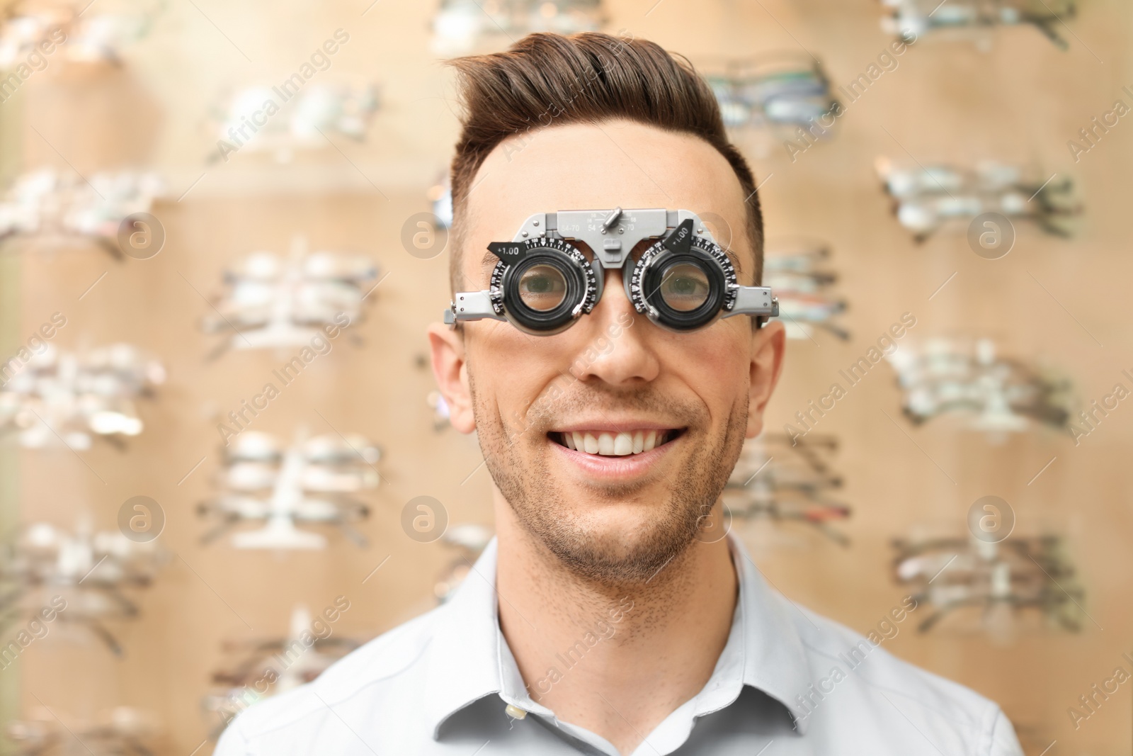 Photo of Young man having eye examination with phoropter in optical store. Ophthalmologist prescription