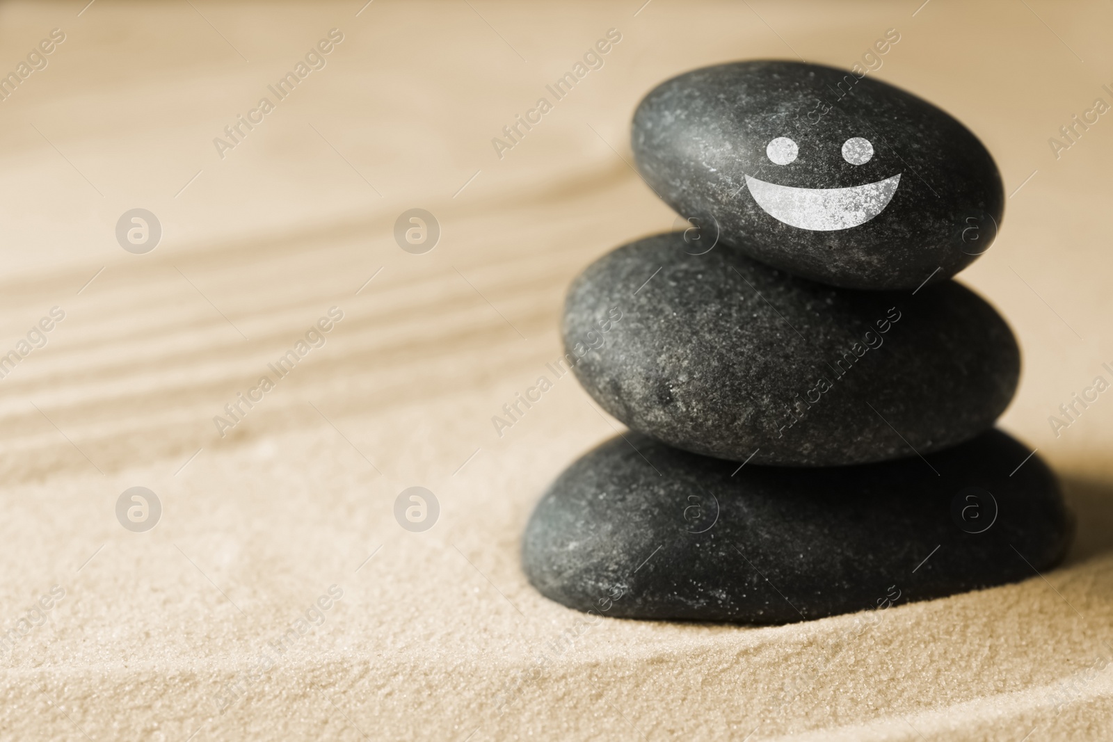 Image of Stack of stones with drawn happy face on sand, space for text. Be in harmony and enjoying your life