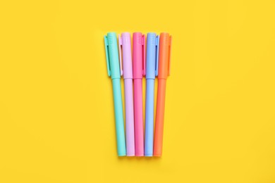 Photo of Many colorful markers on yellow background, flat lay