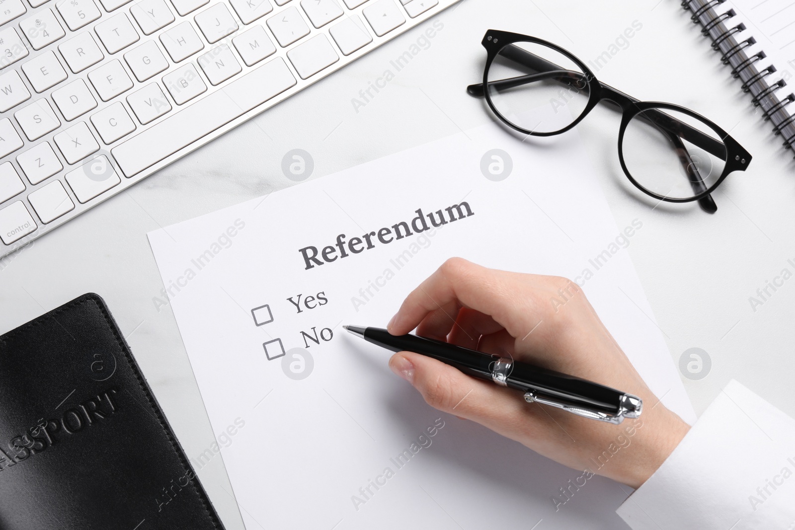 Photo of Woman with referendum ballot making decision at white marble table, closeup