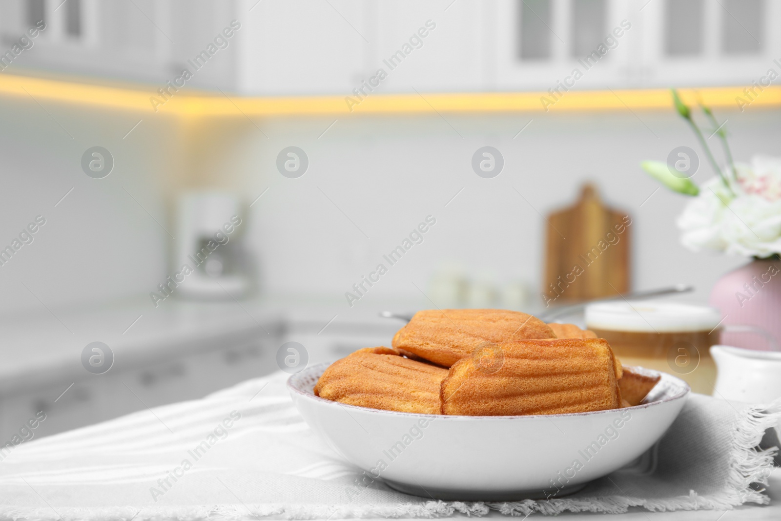 Photo of Tasty madeleine cookies on table in kitchen, space for text