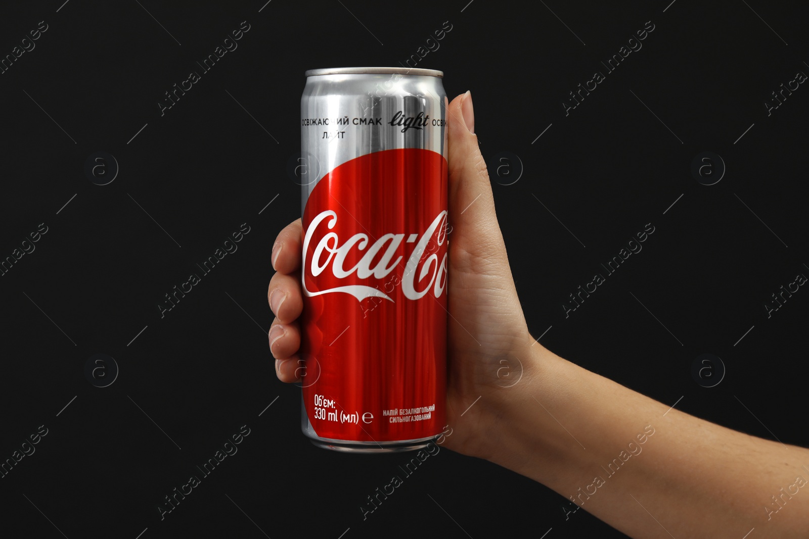 Photo of MYKOLAIV, UKRAINE - NOVEMBER 14, 2018: Woman holding Coca-Cola can on black background