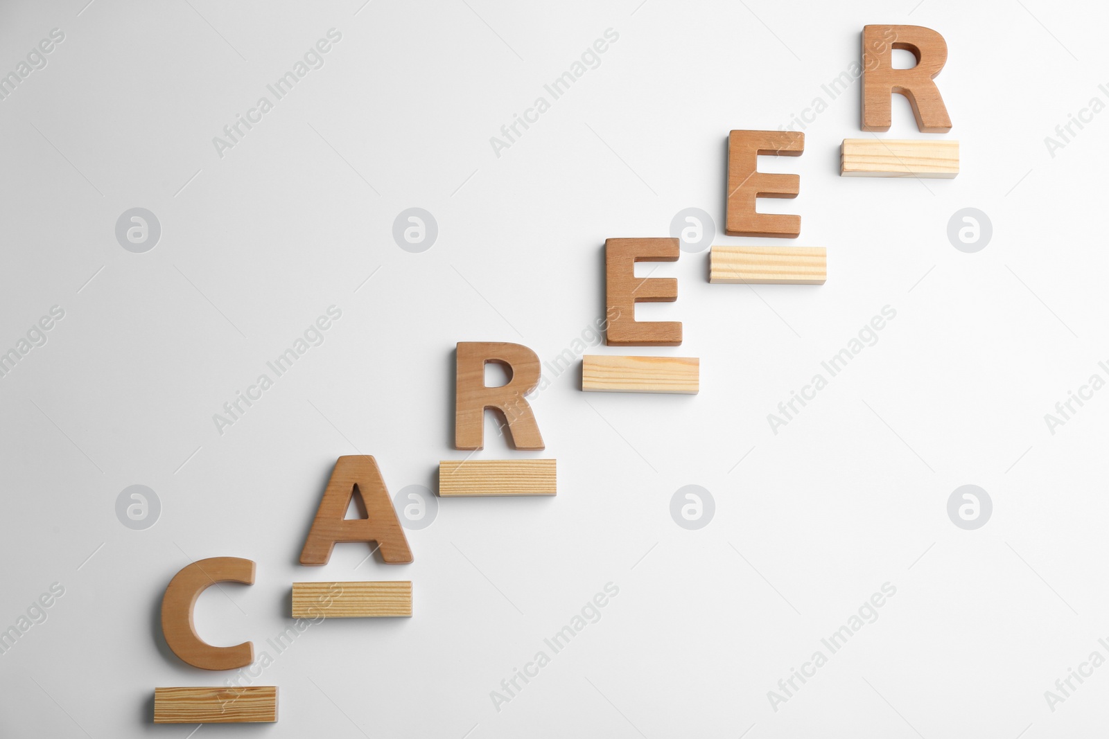 Photo of Stairs of wooden blocks and letters on white background, top view. Career promotion concept