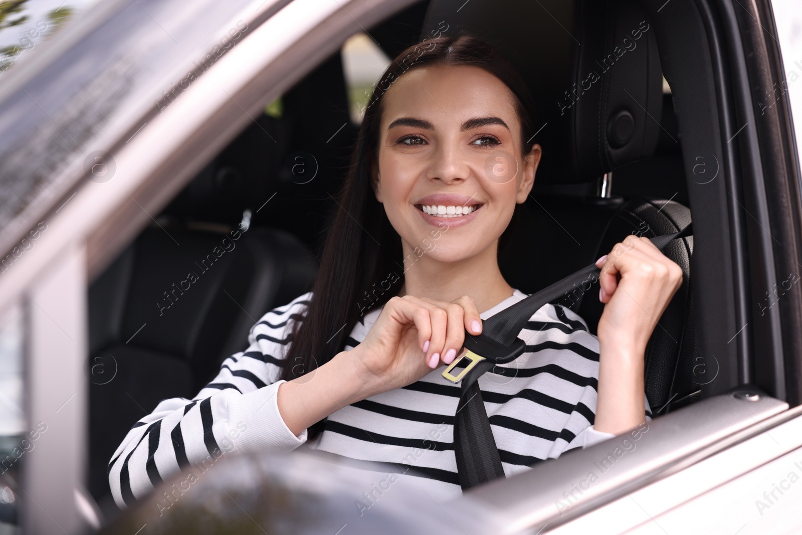 Photo of Woman fastening safety seat belt inside modern car