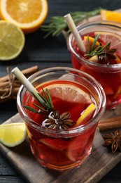 Photo of Aromatic punch drink and ingredients on black wooden table