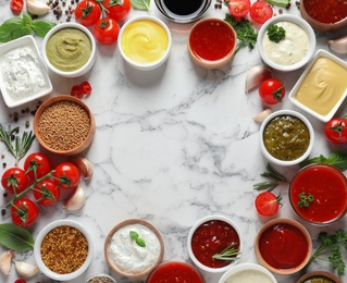 Photo of Frame made with different sauces and ingredients on marble background, flat lay. Space for text