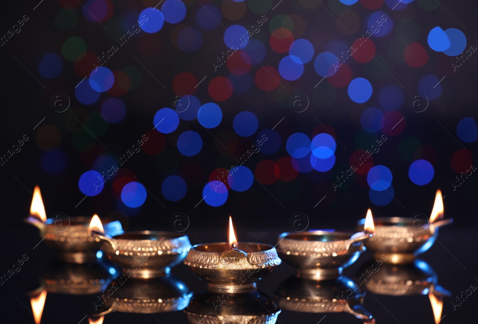 Photo of Many lit diyas on dark background with blurred lights, space for text. Diwali lamps