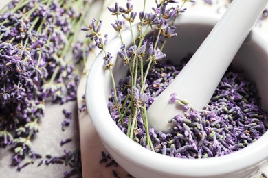 Photo of Mortar and pestle with lavender flowers on grey stone background, closeup. Natural cosmetic