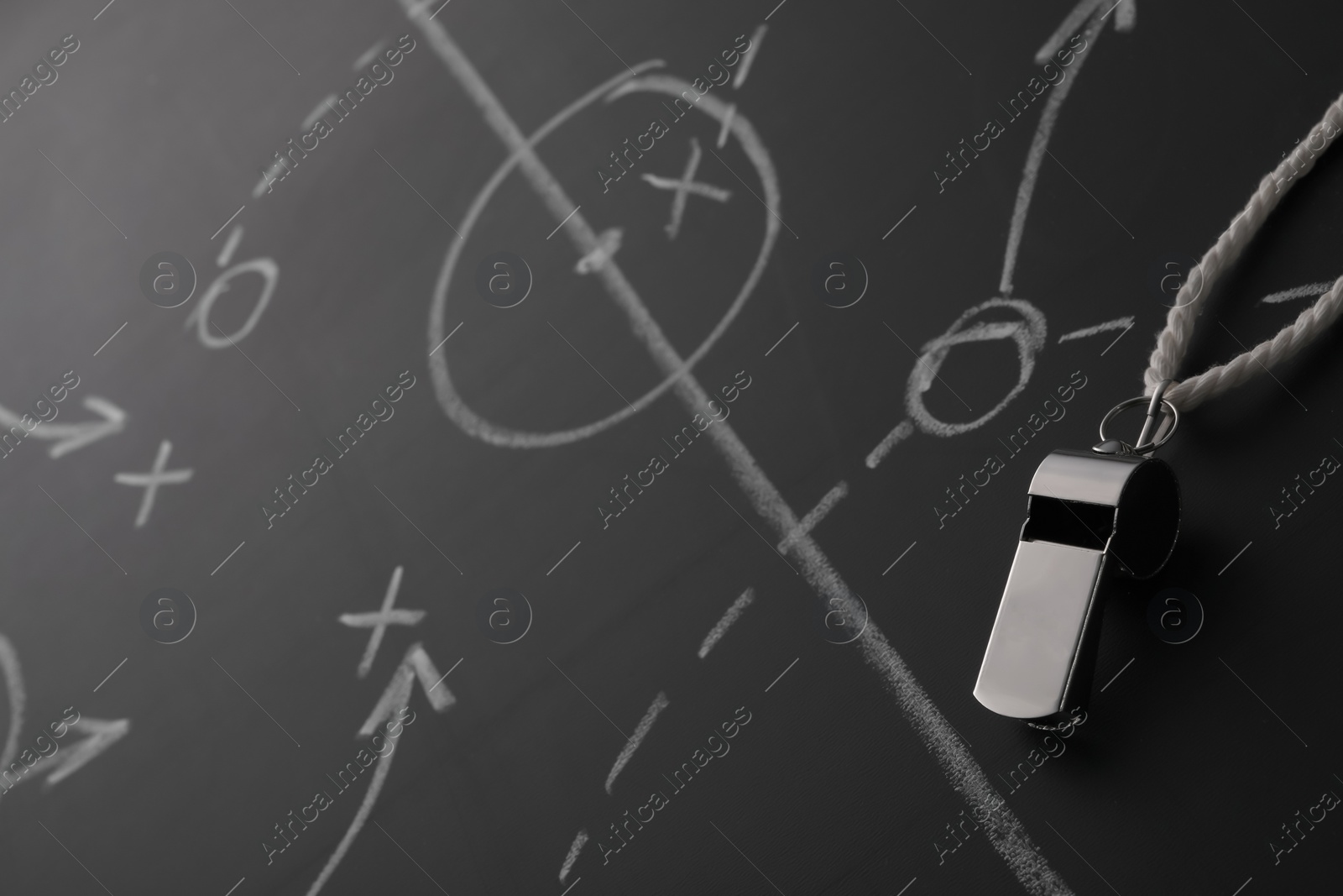 Photo of Referee whistle on chalkboard with game scheme, closeup