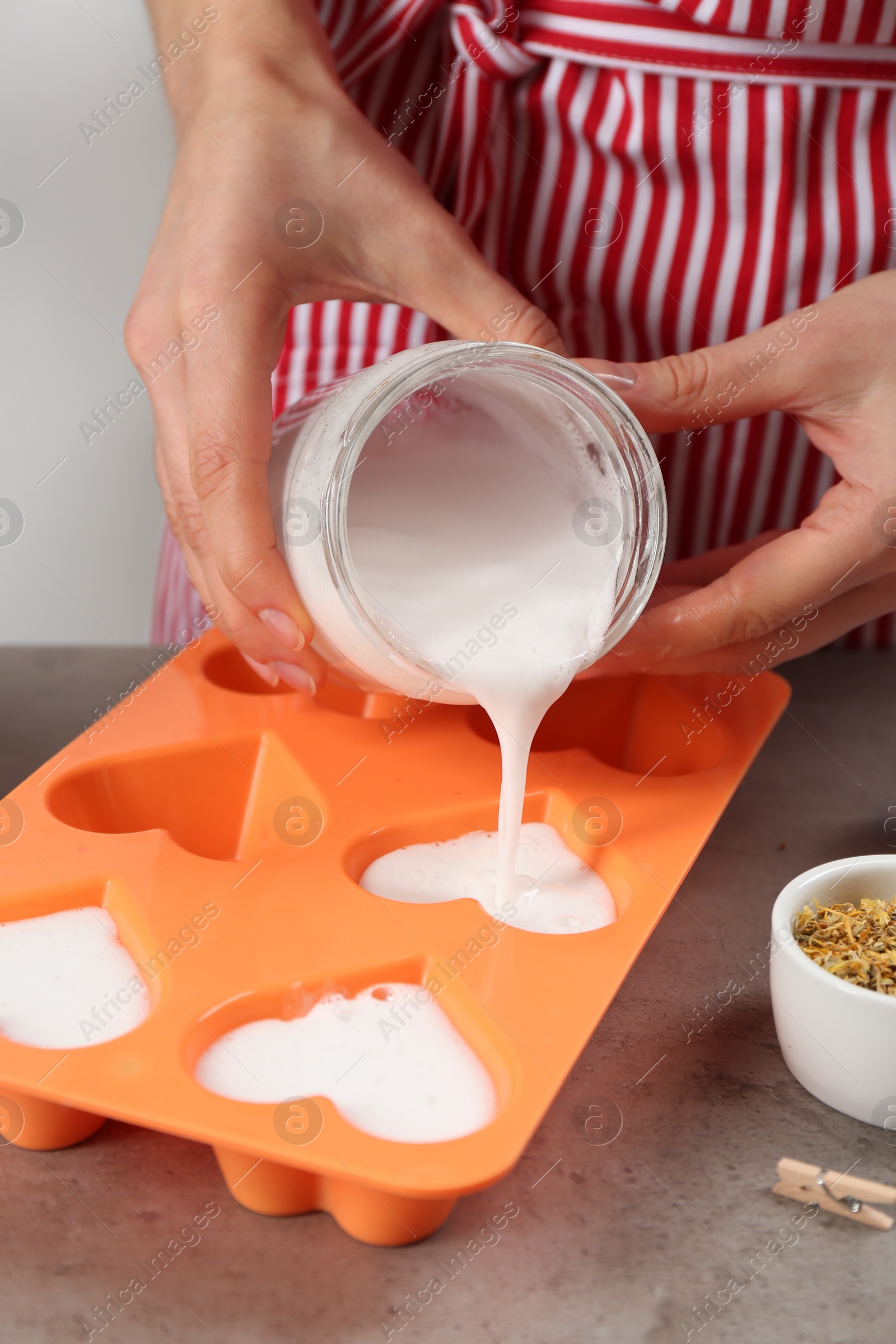 Photo of Woman making natural handmade soap at grey stone table, closeup