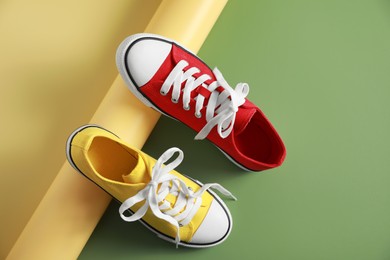 Stylish presentation of red and yellow classic old school sneakers on green background, flat lay