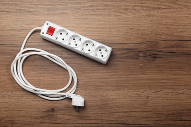 Photo of Power strip with extension cord on wooden floor, top view. Space for text