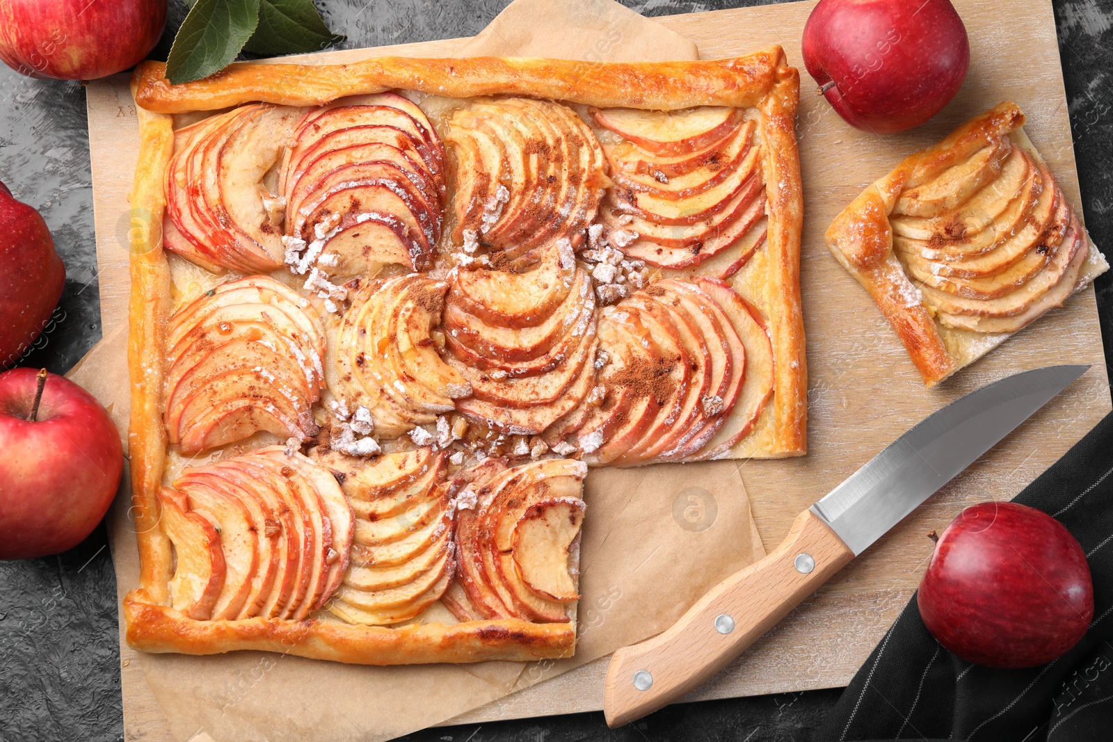 Photo of Tasty apple pie with nuts, fresh fruits and knife on black table, flat lay