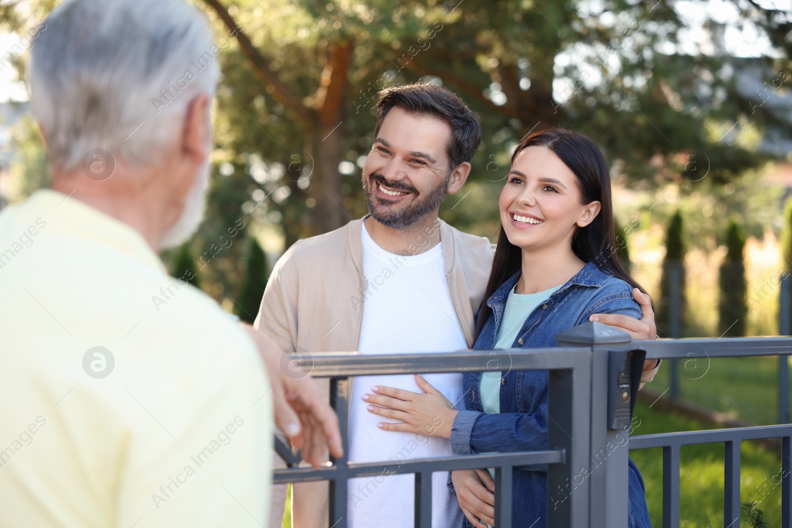 Photo of Friendly relationship with neighbours. Happy couple and senior man near fence outdoors