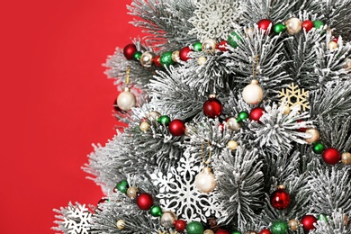 Photo of Beautiful Christmas tree with decor against red background, closeup