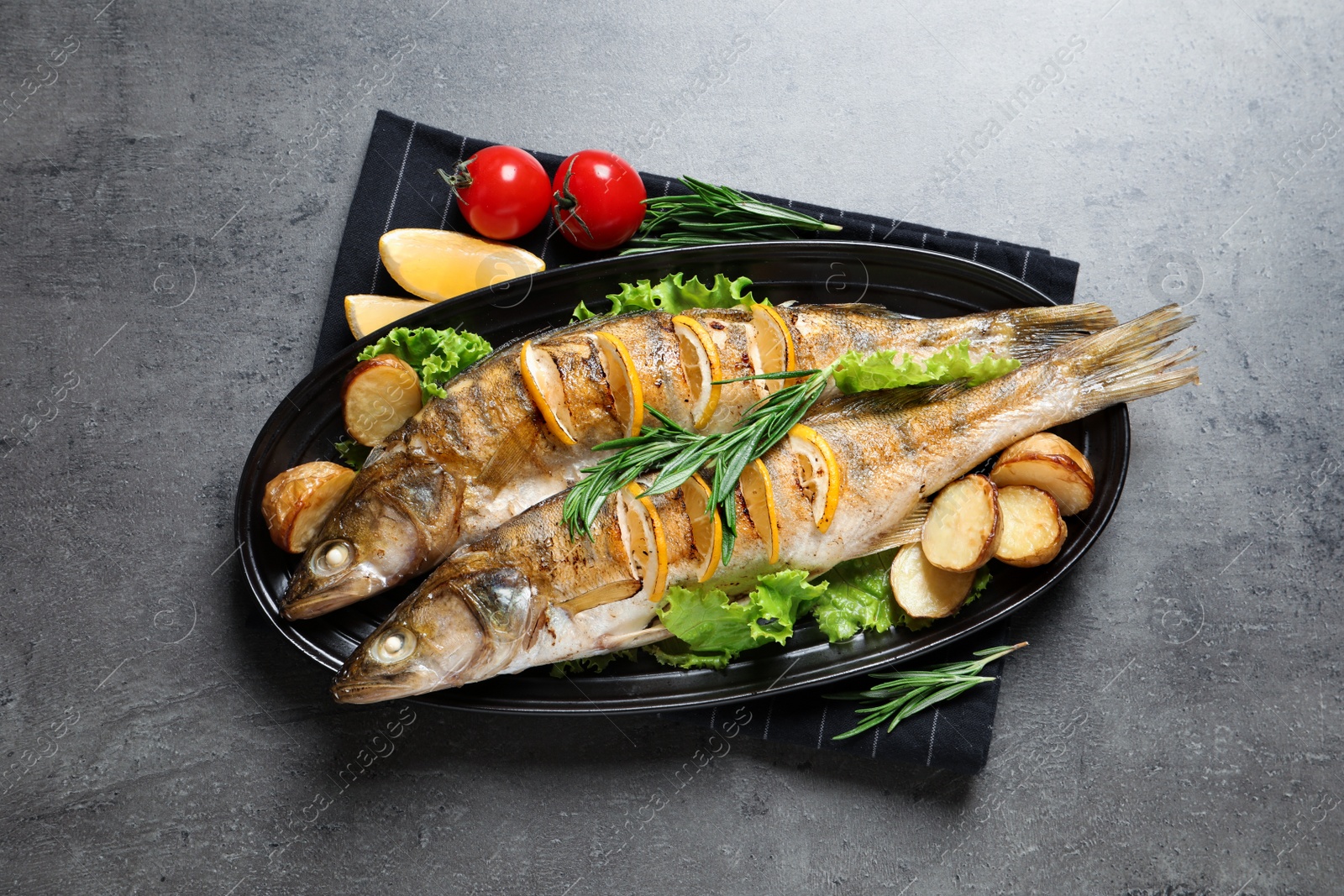 Photo of Tasty homemade roasted pike perches served on grey table, top view. River fish