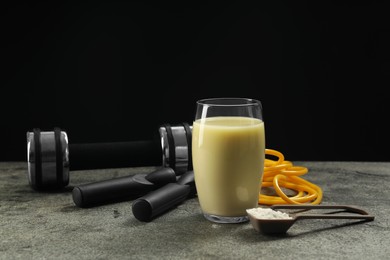 Photo of Tasty shake, sports equipment and powder on grey table against black background. Weight loss