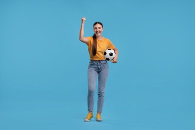 Photo of Happy soccer fan with ball celebrating on light blue background