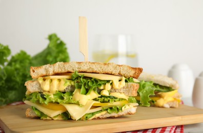 Photo of Wooden board with tasty cheese sandwich on table