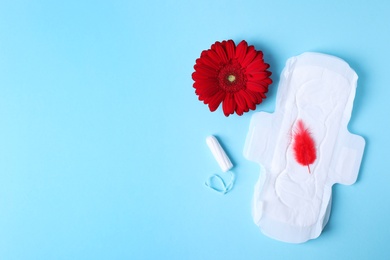 Photo of Different feminine hygiene products, red feather and flower on color background, flat lay with space for text. Gynecological care