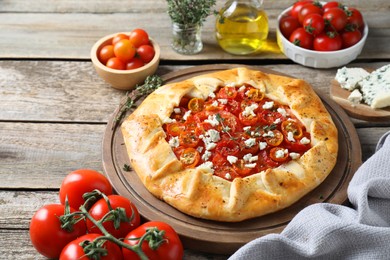 Photo of Tasty galette with tomato, thyme and cheese (Caprese galette) on wooden table, closeup
