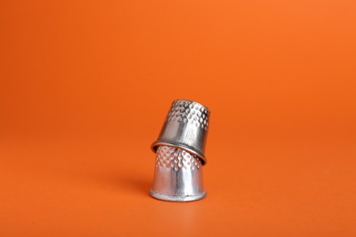 Photo of Sewing thimbles on orange background, closeup view