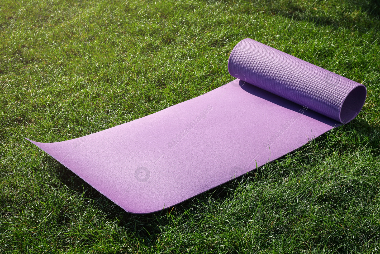 Photo of Bright exercise mat on fresh green grass outdoors