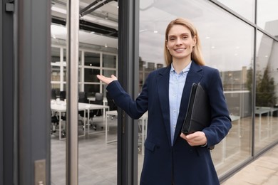 Photo of Female real estate agent with leather portfolio inviting inside