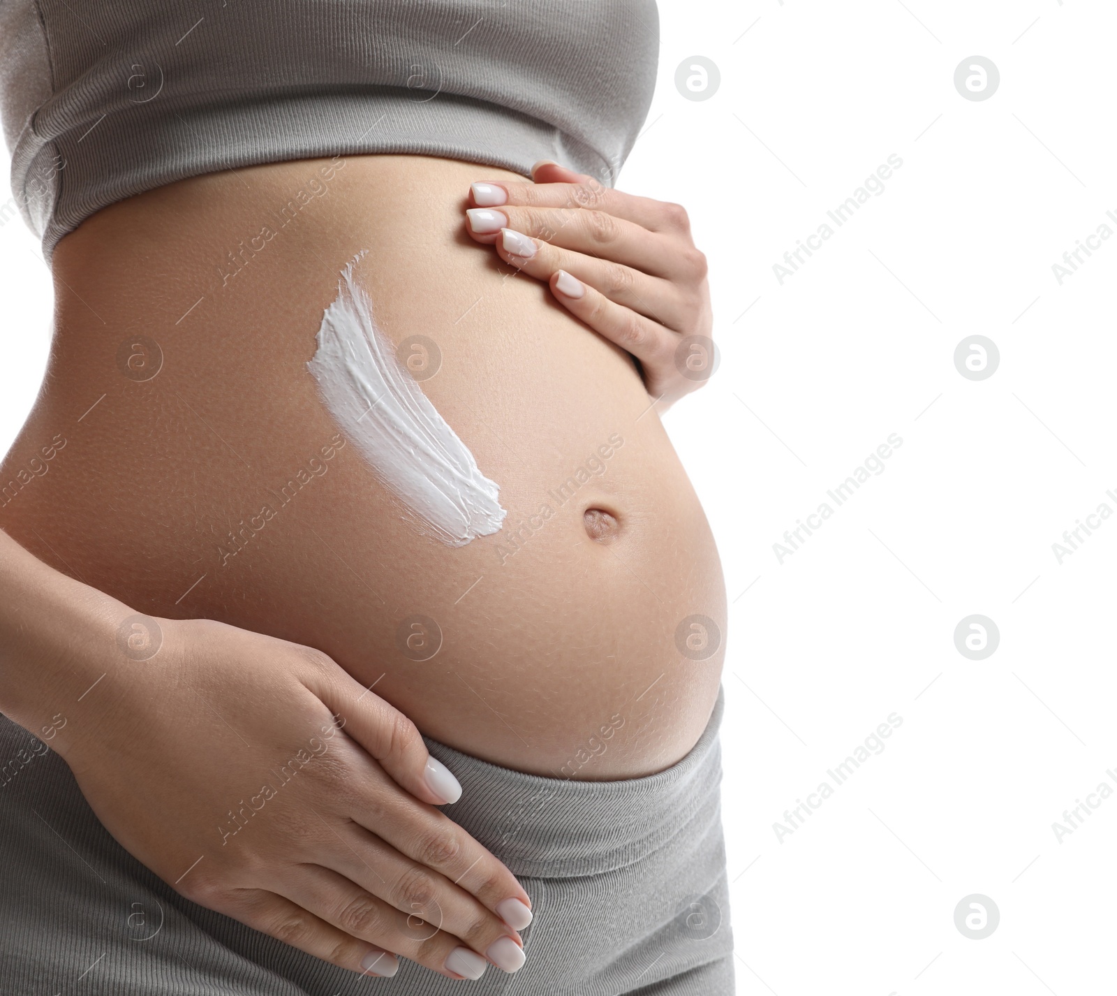 Photo of Pregnant woman applying cosmetic product on belly against white background, closeup