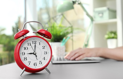 Photo of Red alarm clock on table in office. Time to work