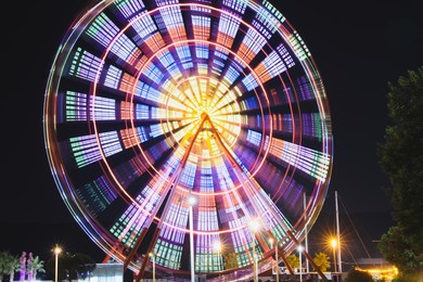 Photo of Beautiful glowing Ferris wheel against dark sky