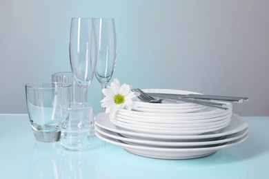 Photo of Set of clean dishes, glasses and cutlery on light blue table