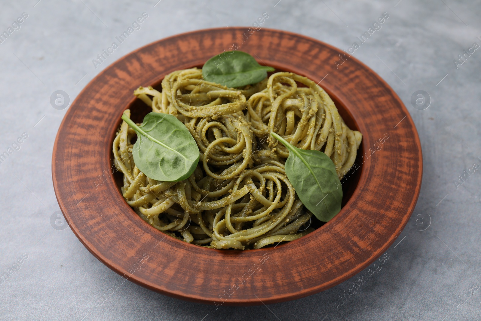 Photo of Tasty pasta with spinach on grey table, closeup