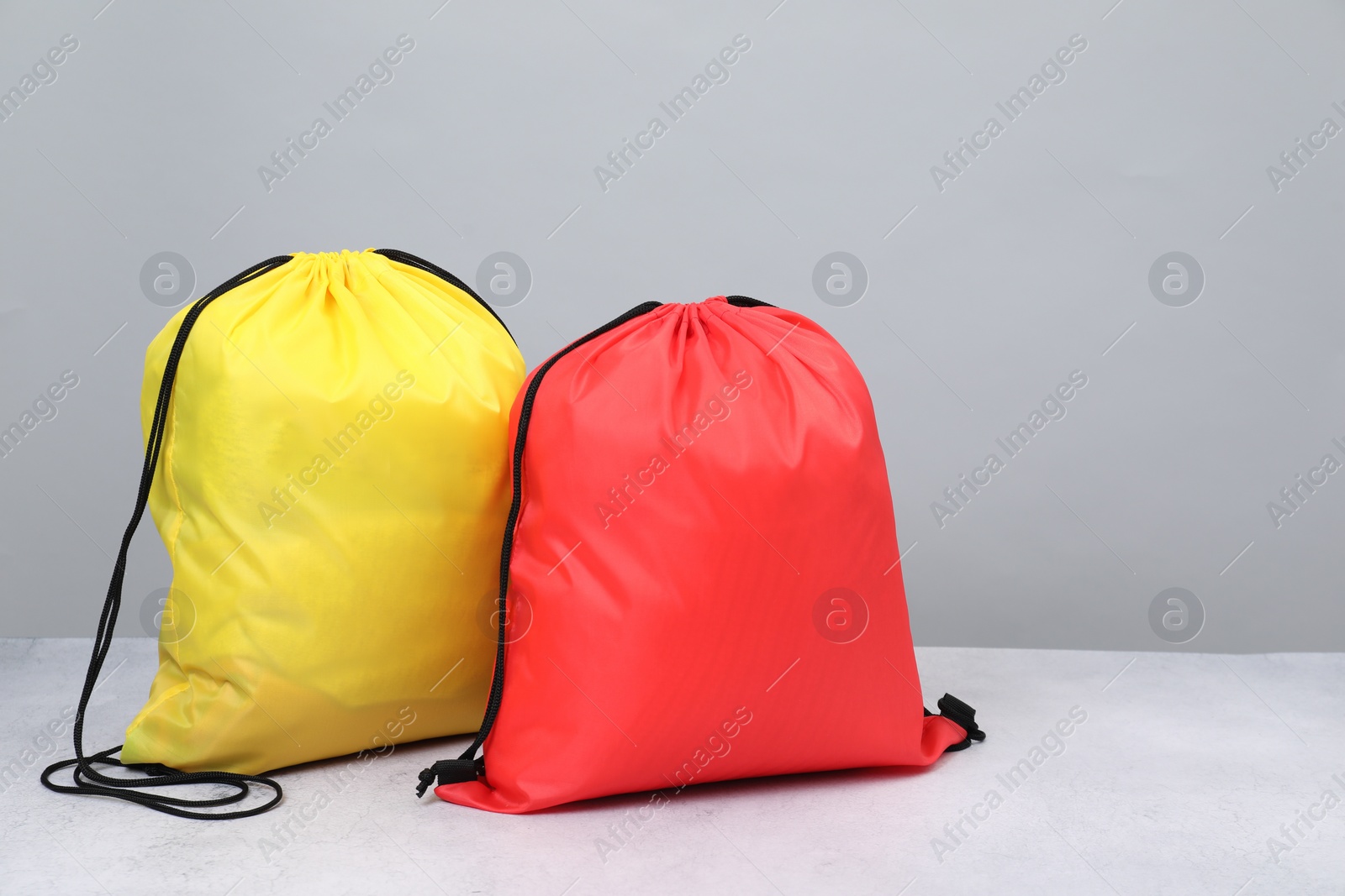 Photo of Two drawstring bags on light textured table. Space for text